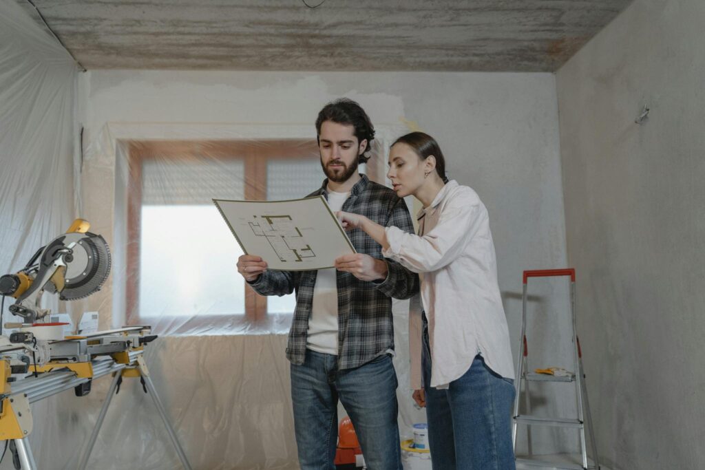 Image actuelle : Man and woman reviewing floor plans in a home renovation setting, discussing project details.